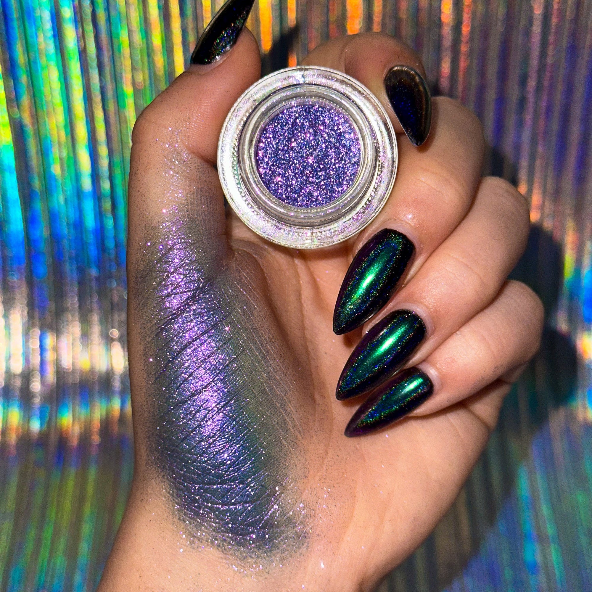 Hand holding a jar of purple glitter with a colorful, reflective background